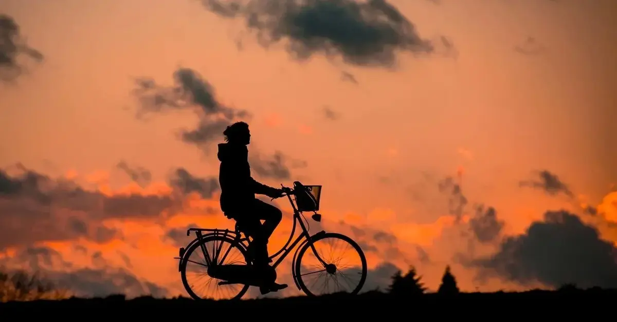 Osoba jadąca na rowerze na tle zachodu słońca