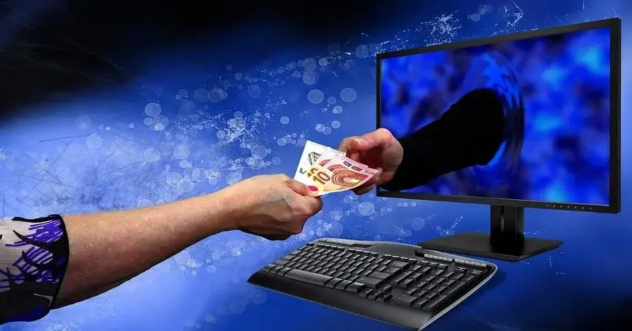 Męska dłoń podaje plik pieniędzy dłoni wychodzącej z monitora komputera symbolizujące różne metody płatności