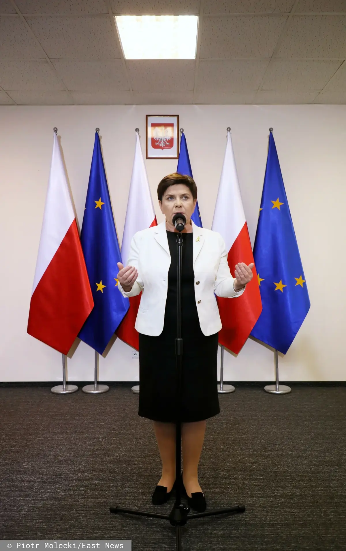 Beata Szydło na tle flag Polski i UE