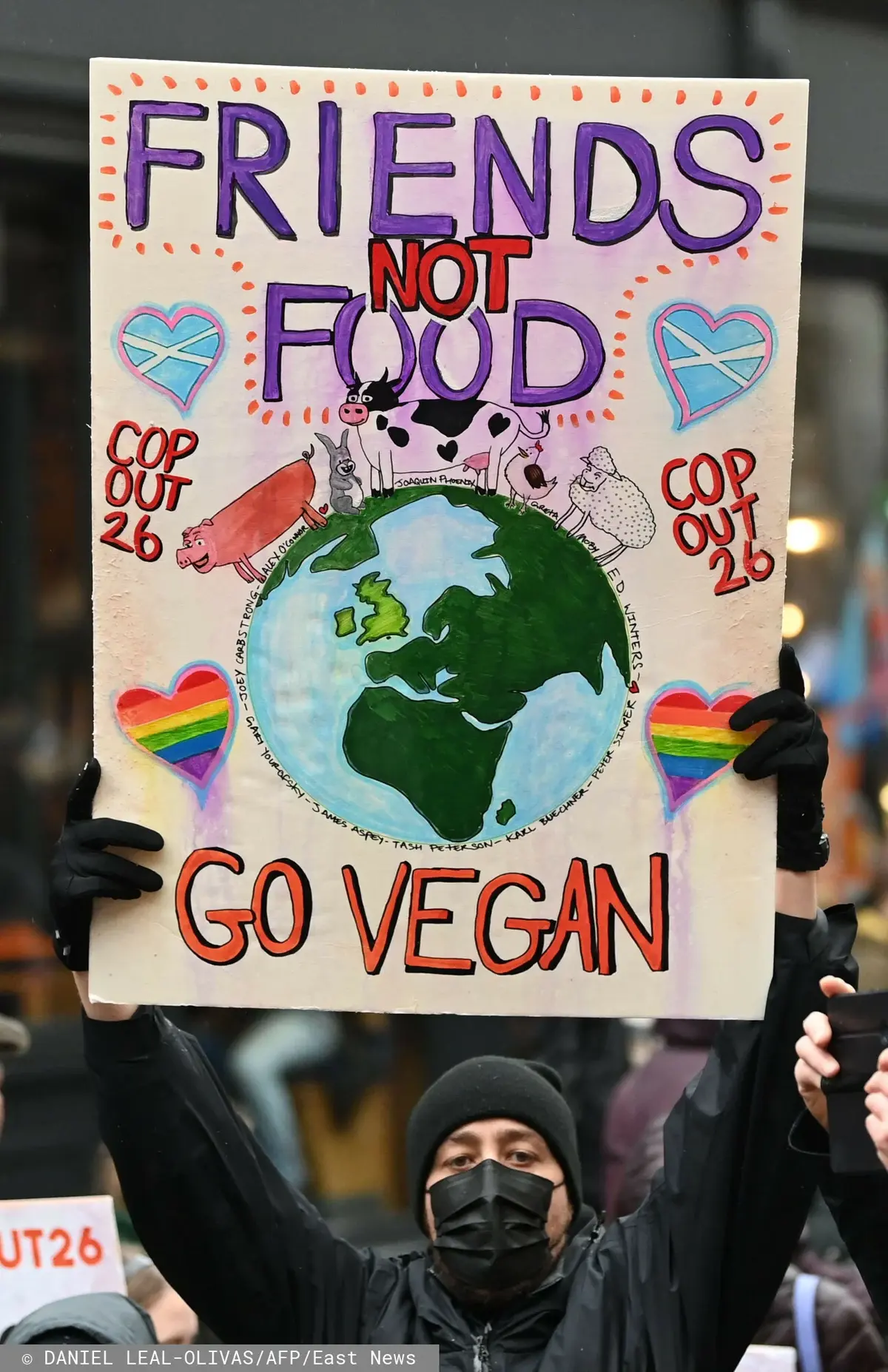 Mężczyzna na COP26, trzymający tabliczkę z napisem Friends not Food - Go Vegan