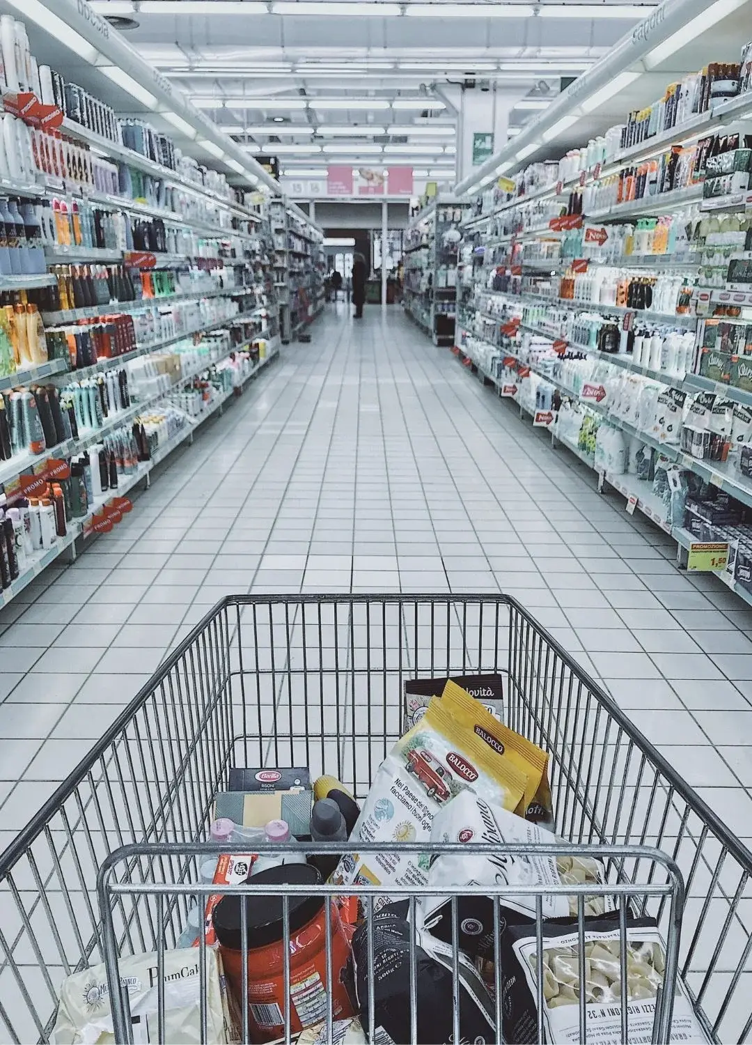 Wózek sklepowy wypełniony produktami w alejce w sklepie
