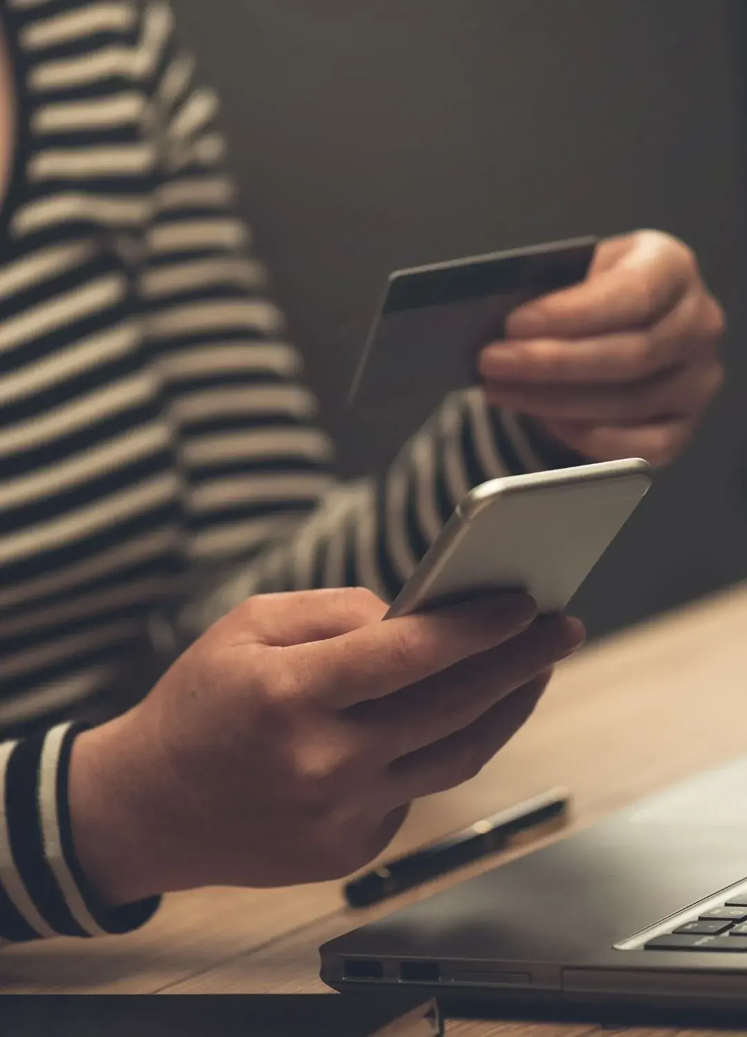 Kobieta trzymająca w smartfona i kartę przy biurku
