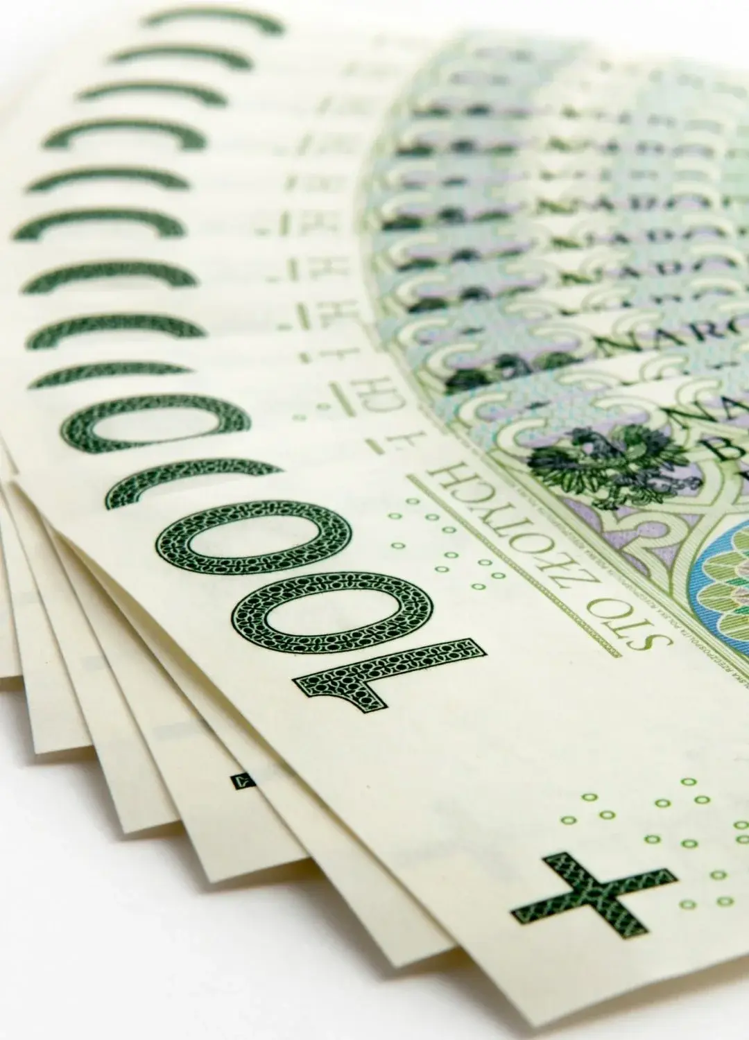 Banknoty stuzłotowe rozłożone na białym stole