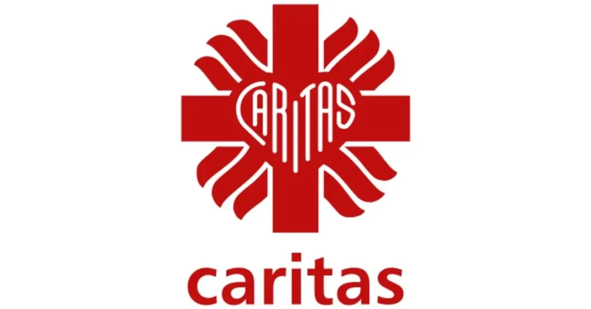 Czerwono-białe logo Caritas w kształcie serca na krzyżu