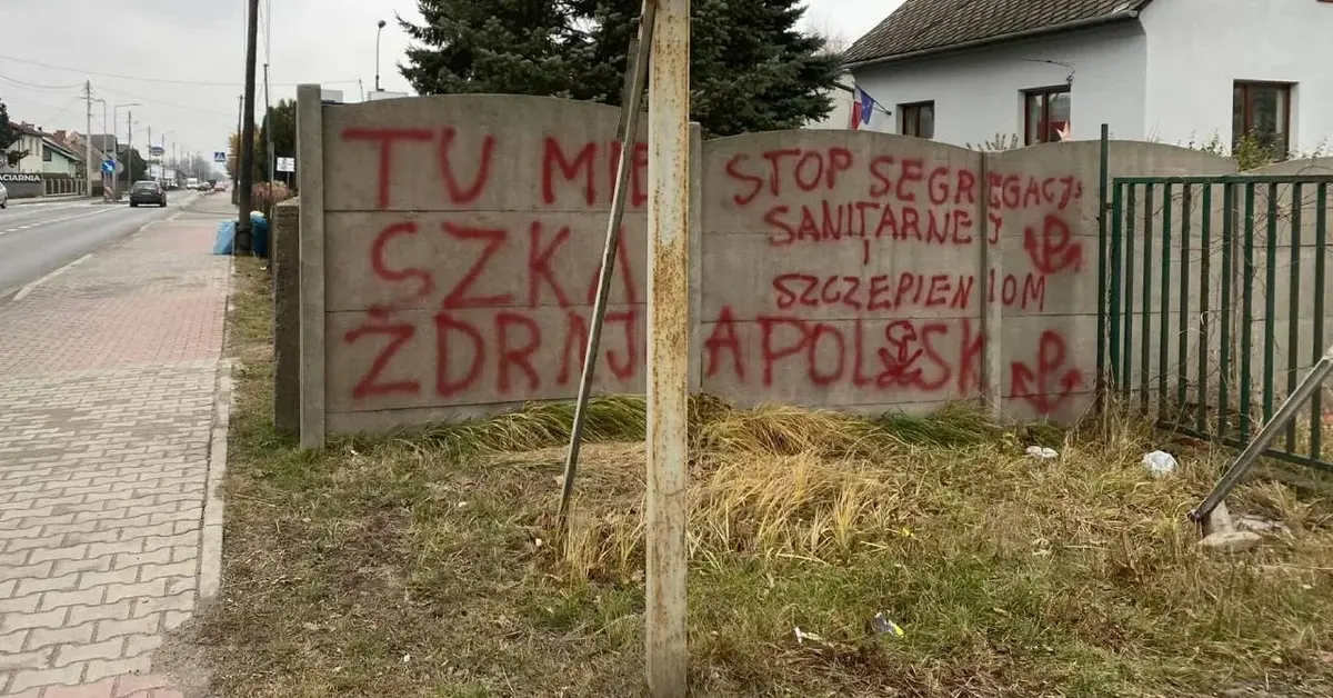 Czerwony napis na elewacji ogrodzenia domu Doroty Niedzieli.
