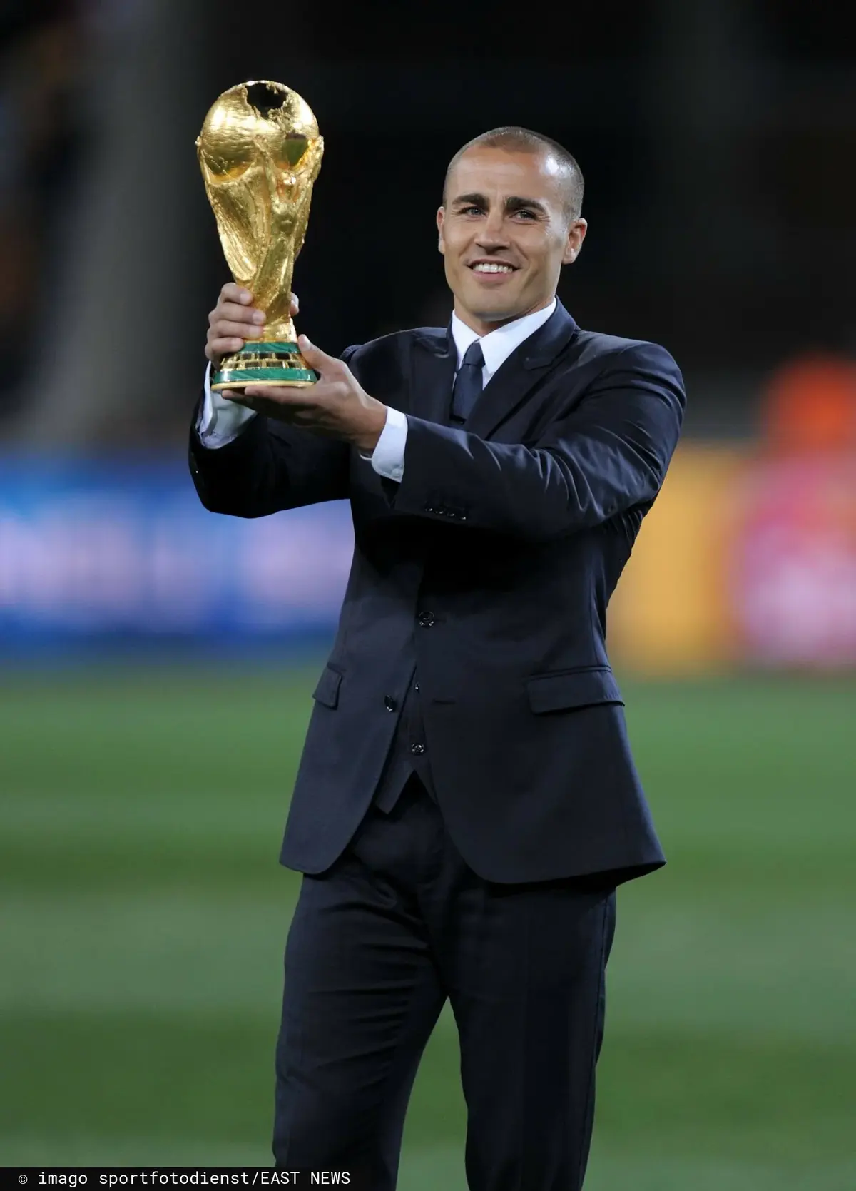 Fabio Cannavaro w garniturze trzymając puchar