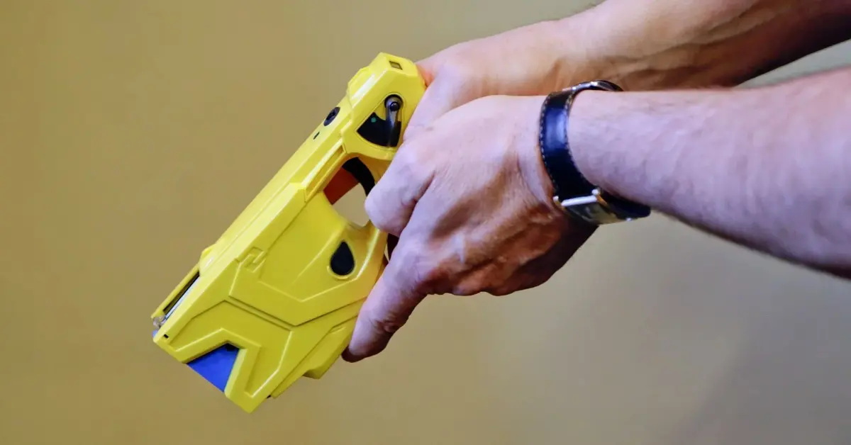 żółty taser trzymany w dłoniach przez mężczyznę