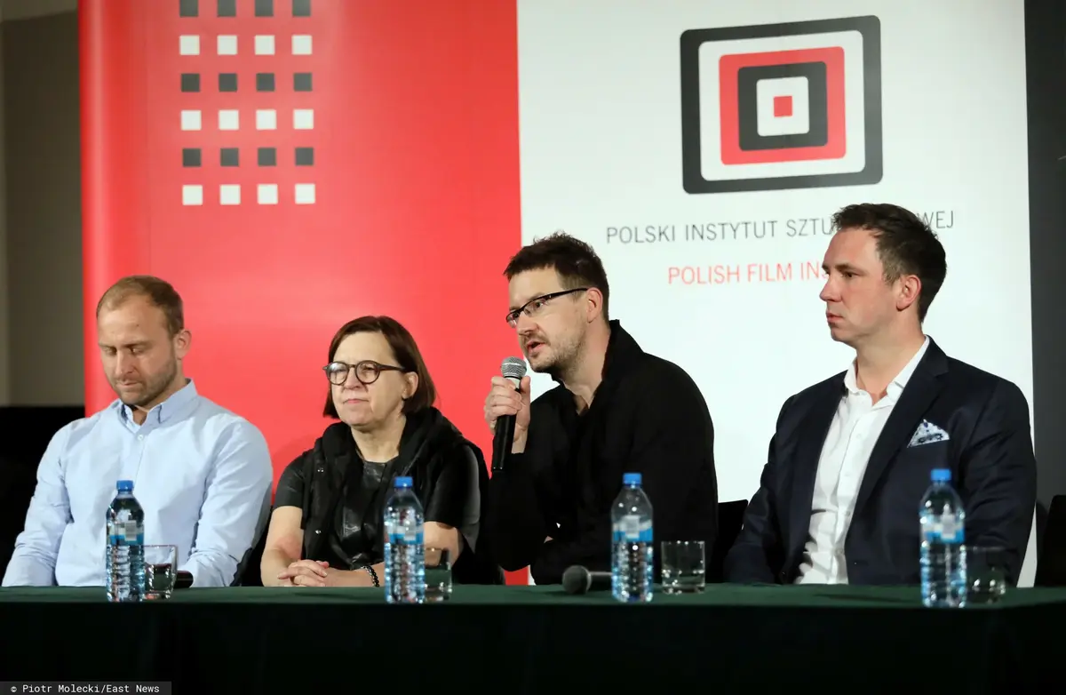 Ludzie siedzący na tle logo PISF.