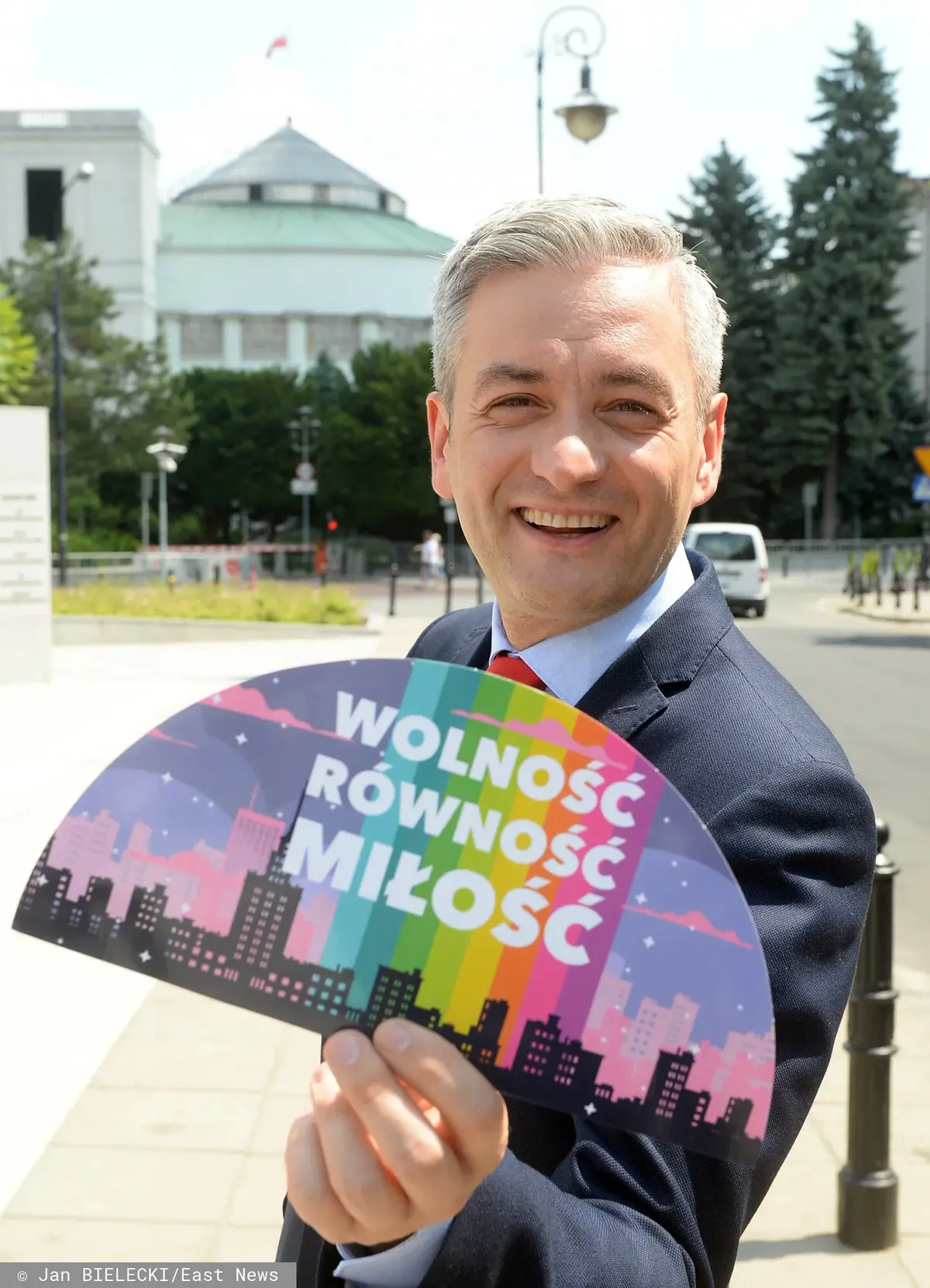 Rober Biedroń trzymający kartkę z napisem WOLNOŚĆ RÓWNOŚĆ MIŁOŚĆ