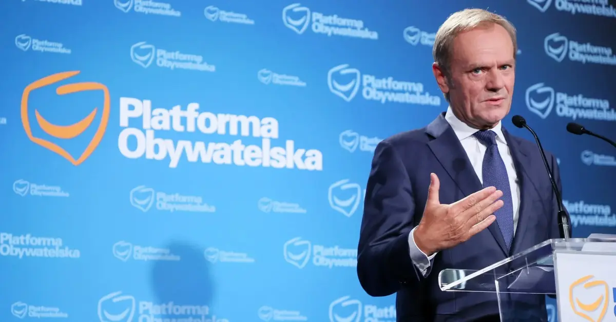 Donald Tusk podczas konferencji prasowej na tle logo PO przy mównicy z logiem PO 