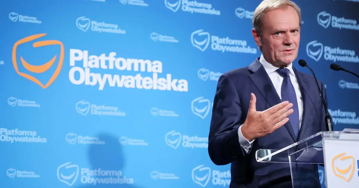 Donald Tusk podczas konferencji prasowej na tle logo PO przy mównicy z logiem PO 