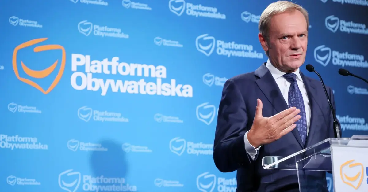 Donald Tusk podczas konferencji prasowej na tle logo PO przy mównicy z logiem PO 