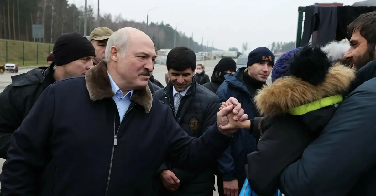 aleksander łukaszenka trzyma za rączkę dziecko w tłumie migrantów