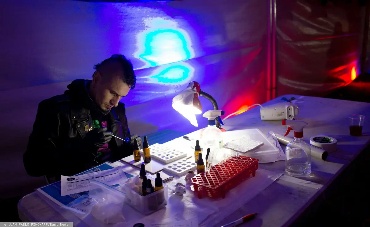 Mężczyzna siedzi przy stole i bada MDMA.