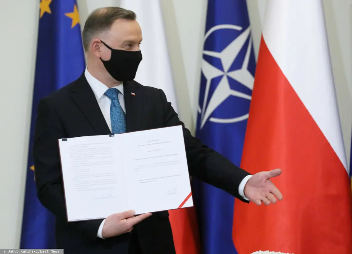 Andrzej Duda w maseczce trzyma podpisane porozumienie.