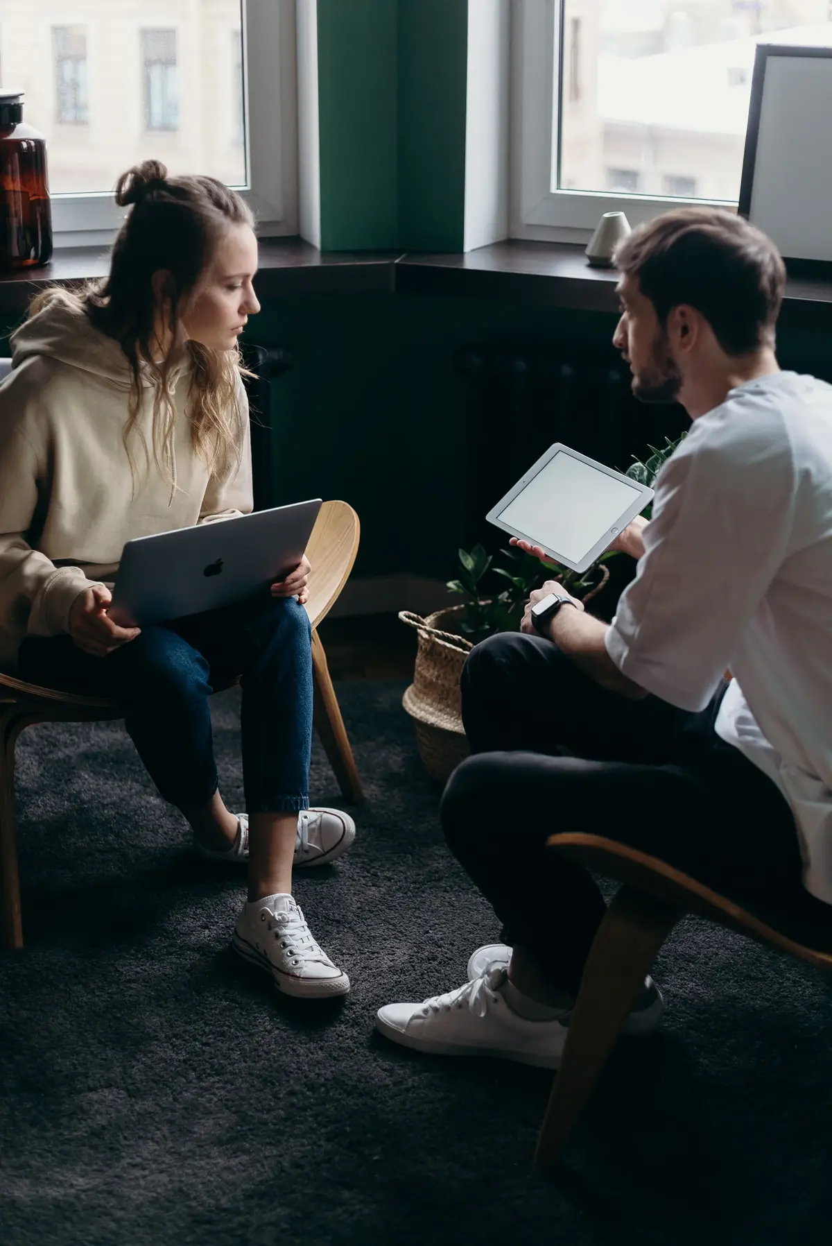 Dwoje ludzi rozmawia, z laptopami i tabletem 