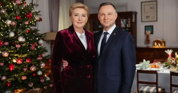 Andrzej Duda obejmuje Agate Kornhauser-Dudę obok choinki z prezentami i przy wigilijnym stole