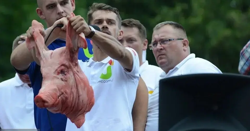 lider agrounii michał kołodziejczak trzyma odciętą świńską głowę za uszy i mówi do mikrofonu na wiecu