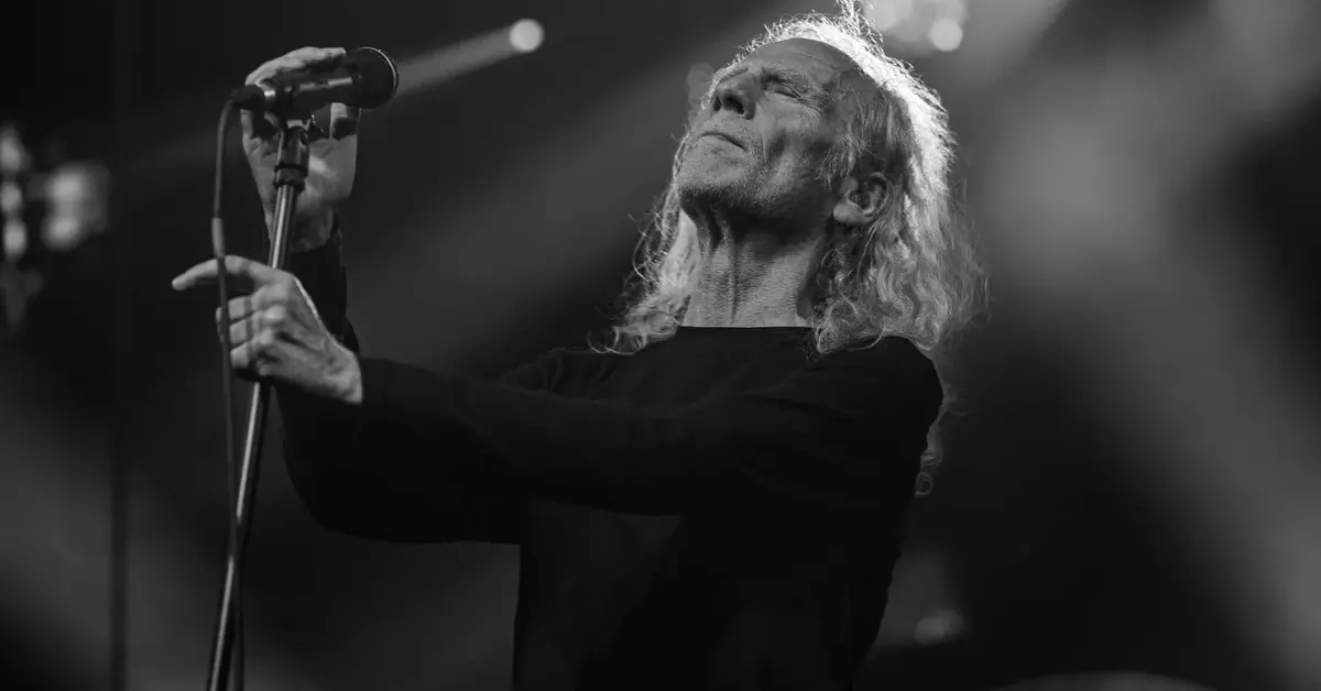 Kostrzewski trzymający mikrofon na scenie z zamkniętymi oczami