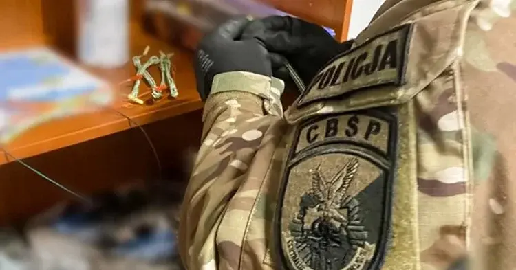 Policjant CBŚP w mundurze operacyjnym przeszukuje półkę z chemikaliami do produkcji materiałów wybuchowych 