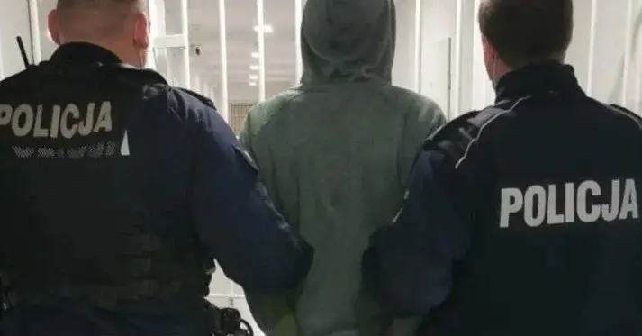 zakapturzony mężczyzna tyłem prowadzony przez dwóch policjantów