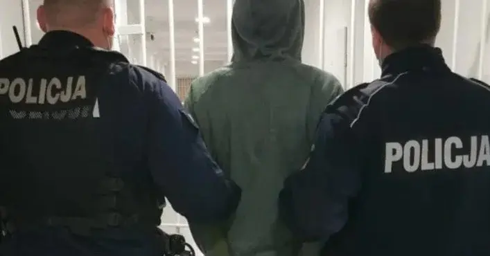 zakapturzony mężczyzna tyłem prowadzony przez dwóch policjantów