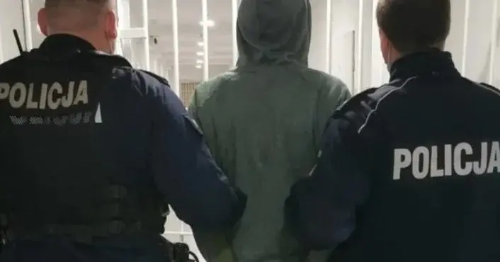 zakapturzony mężczyzna tyłem prowadzony przez dwóch policjantów