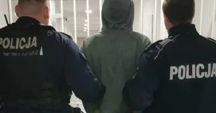 zakapturzony mężczyzna tyłem prowadzony przez dwóch policjantów