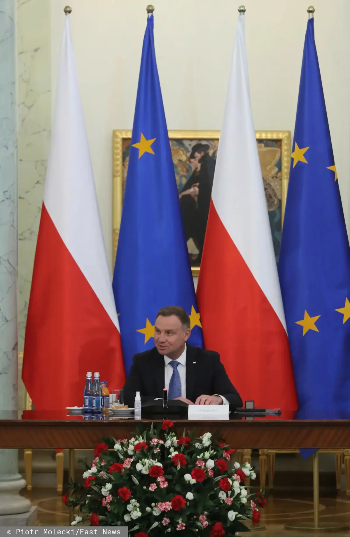 Andrzej Duda na przemówieniu na tle flag Polski i UE