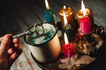 Lanie wosku przez klucz, na stoliku ustawionych jest pięć zapalonych świeczek 