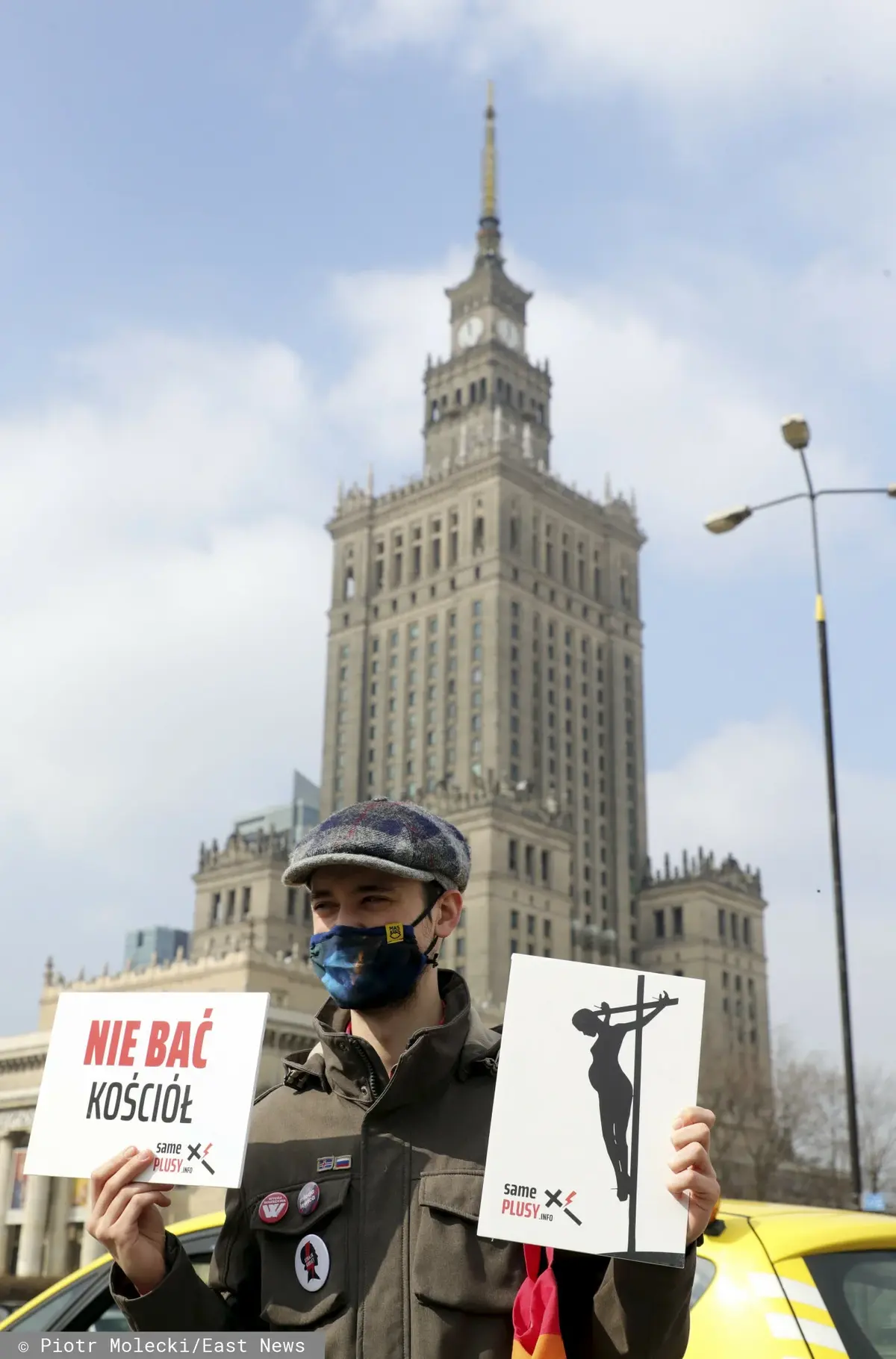 Mężczyzna strajkuje, w dłoni trzyma plakat z napisem "nie bać kościół", w tle Pałac Kultury