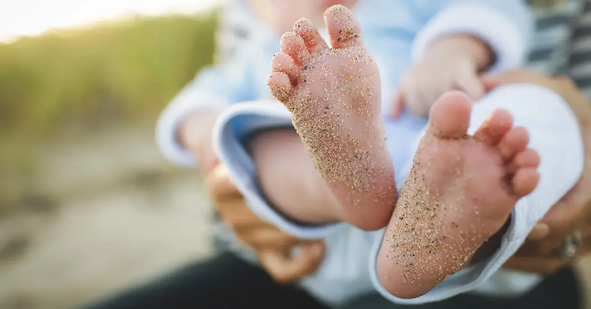 stópki małego dziecka ubrudzone w piasku
