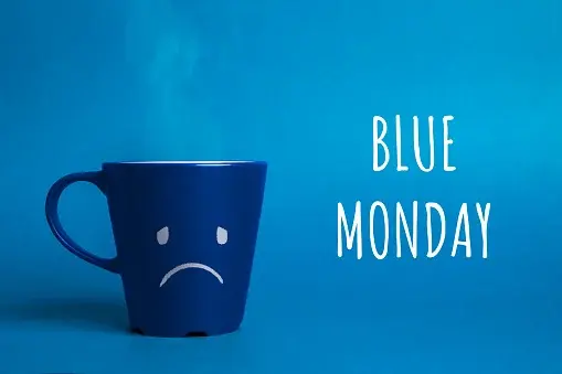 Napis „Blue Monday", a obok niebieski kubek ze smutną buźką