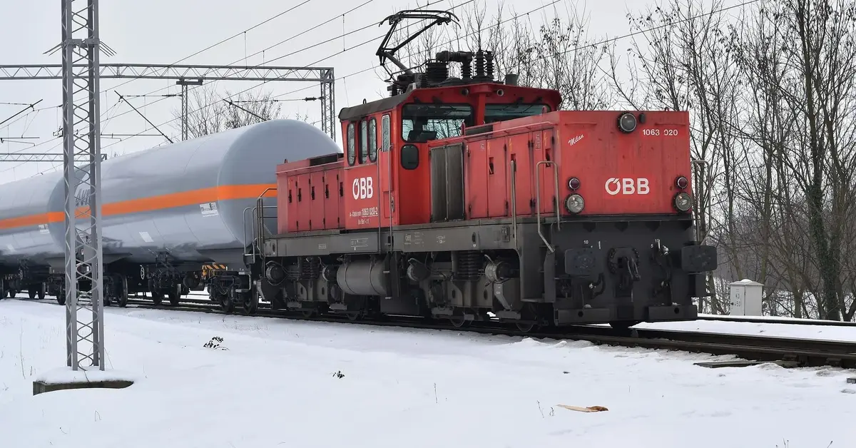 czerwona lokomotywa ciągnie cysterny w śnieżnej scenerii