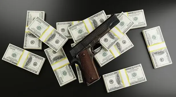 Pieniądze i pistolet, leżące na czarnym blacie