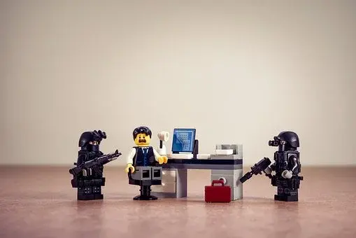 Postacie z klocków Lego przedstawiające dwie osoby w mundurach i jedną przy komputerze