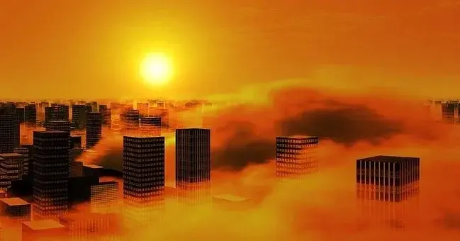 Smog nad miastem, w którym jest wiele wysokich biurowców i apartamentowców,  w tle słońce za chmurami