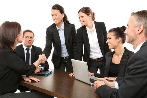 Cztery kobiety i dwóch mężczyzn w biznesowych strojach, w trakcie spotkania w pracy