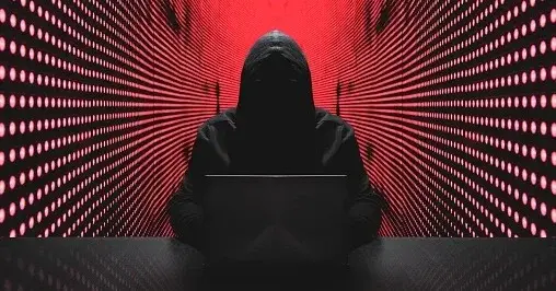 Mężczyzna w kapturze przypominający hakera w trakcie cyberataku