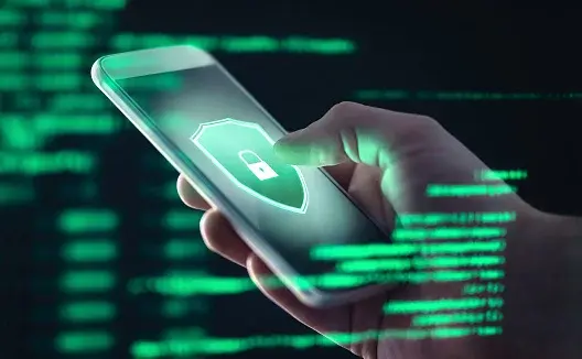 Mężczyzna trzyma w dłoni smartfon z zielonym zabezpieczeniem przed cyberatakami