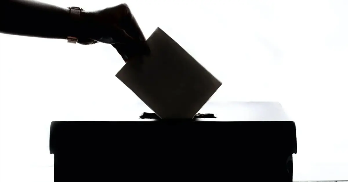 Ktoś wrzuca kartę głosowania do urny