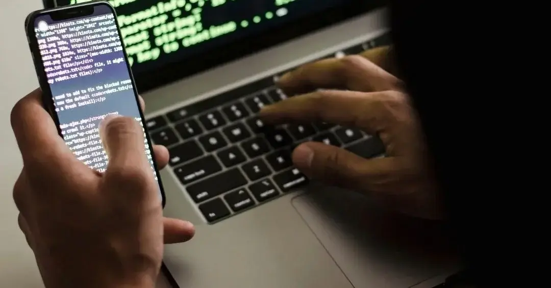 Hacker trzymający telefon przed komputerem