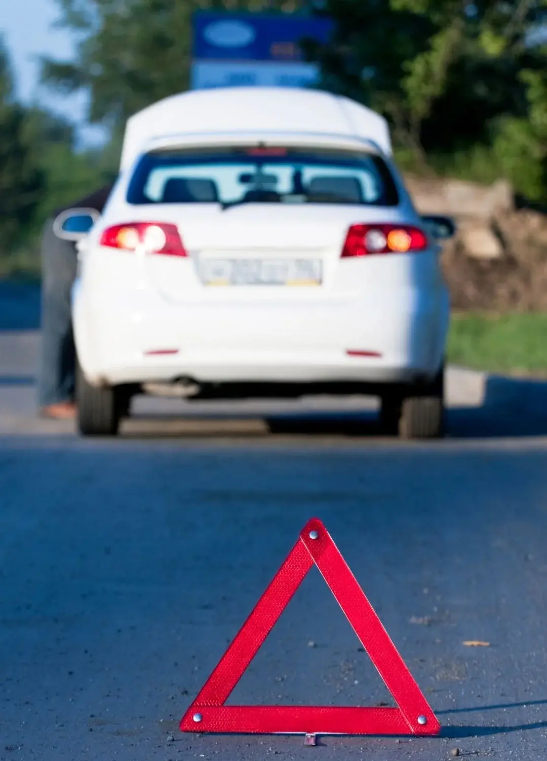 Czerwony trójkąt ostrzegający o wypadku samochodowym na tle białego pojazdu