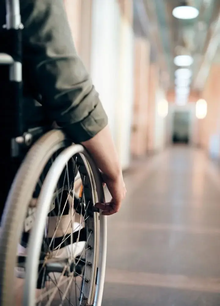 Osoba poruszająca się na wózku inwalidzkim po korytarzu
