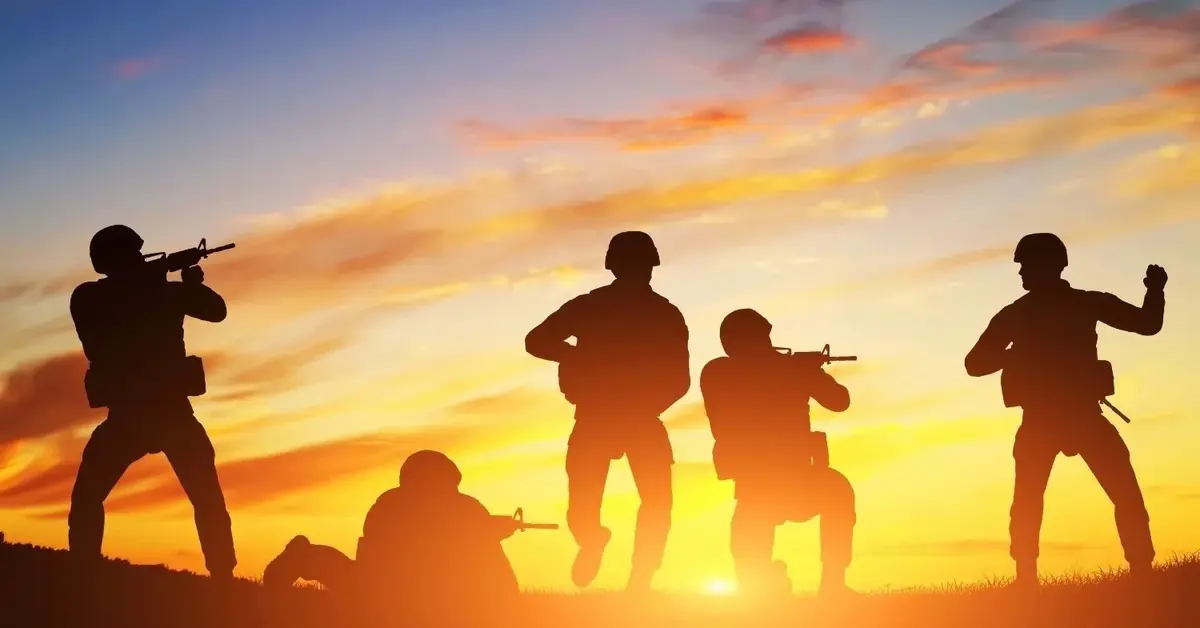 Sylwetki żołnierzy na tle wschodzącego słońca
