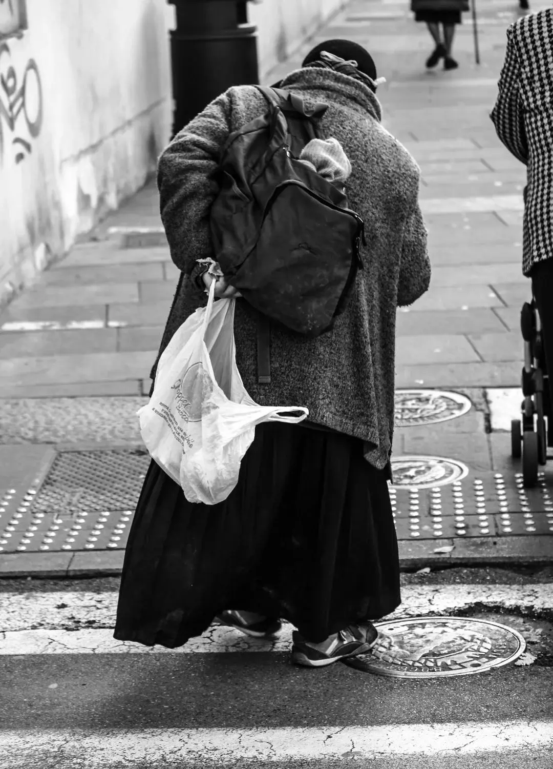 Bezdomna kobieta przechodząca przez ulicę