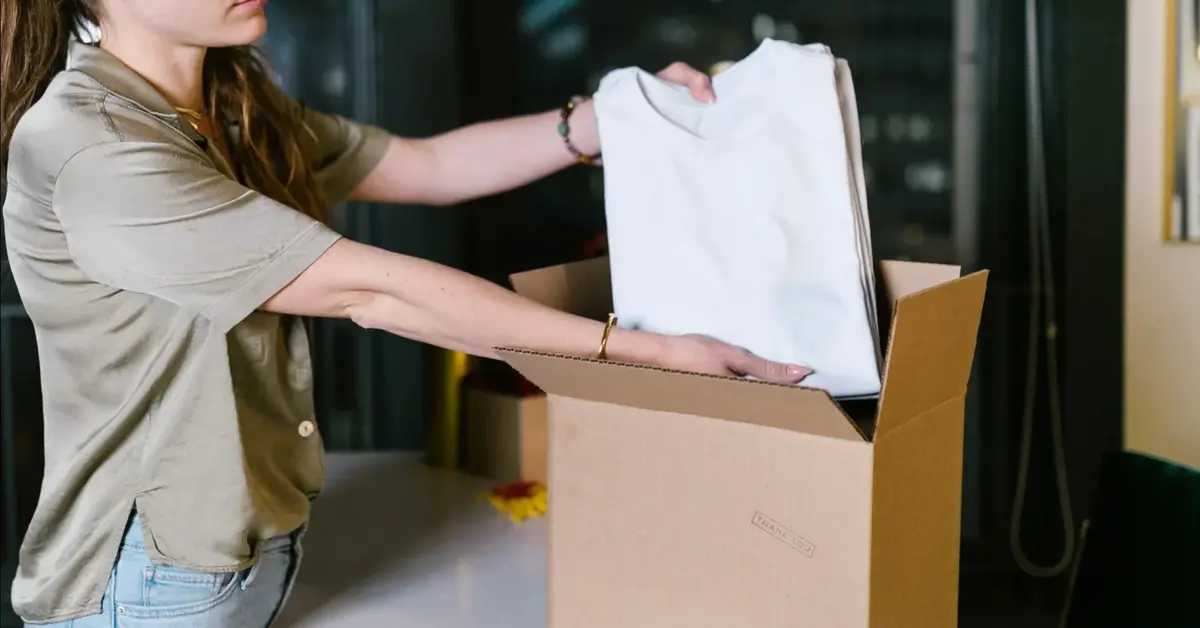 Kobieta pakuje koszulkę do kartonu