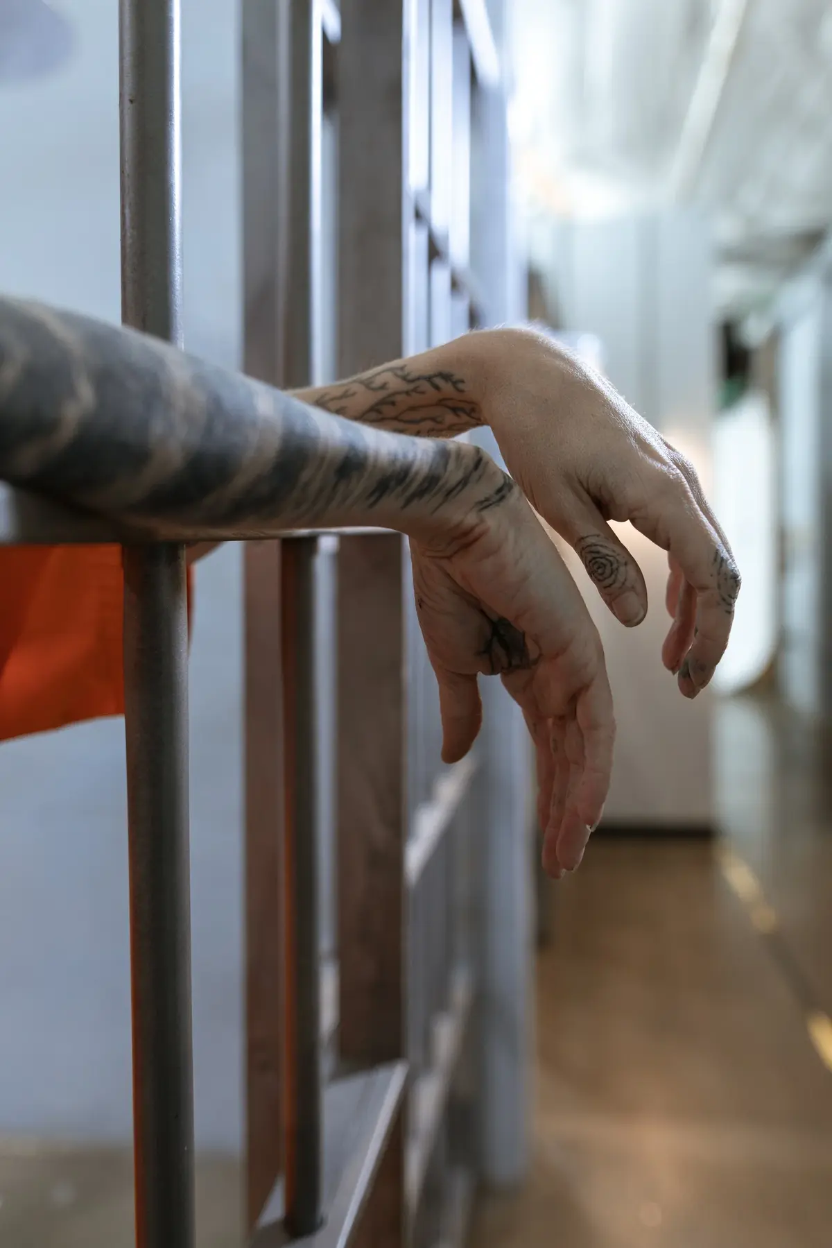 Więzień trzyma dłonie na kratach