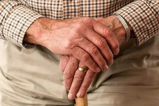 Senior opierający się rękoma o laskę 