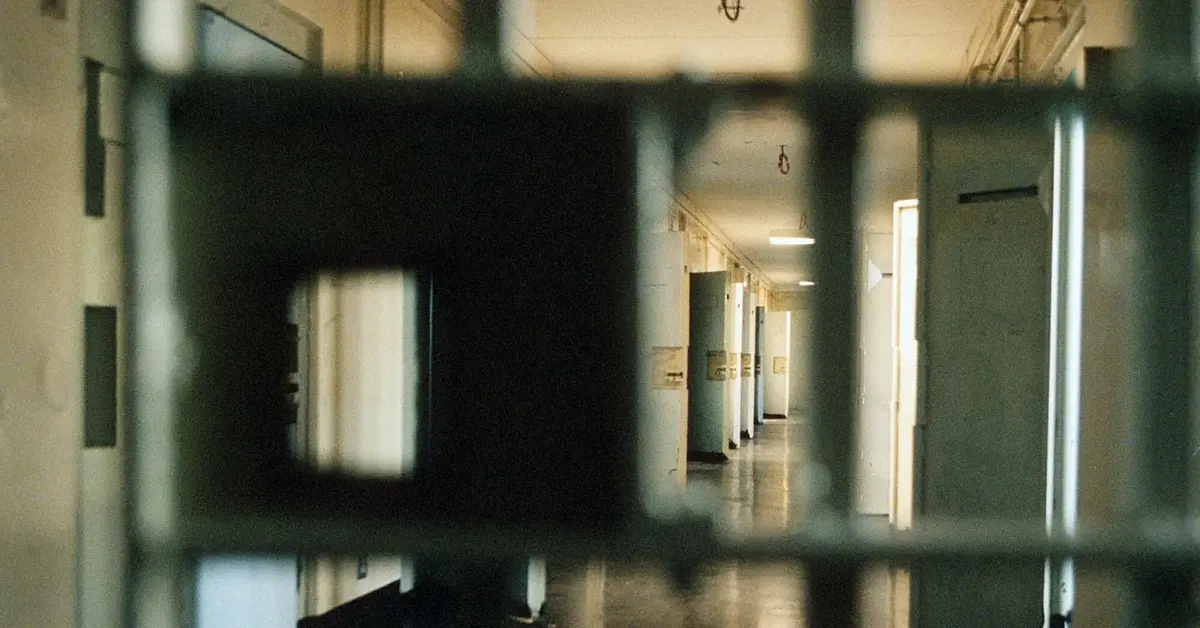 więzienna krata a za nią korytarz z drzwiami do cel